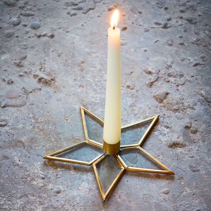 a lit candle sitting in the middle of a star shaped object on top of a stone floor