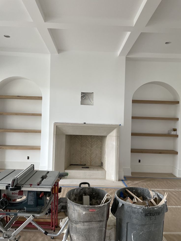 two buckets are sitting on the floor in front of some shelves and a fireplace