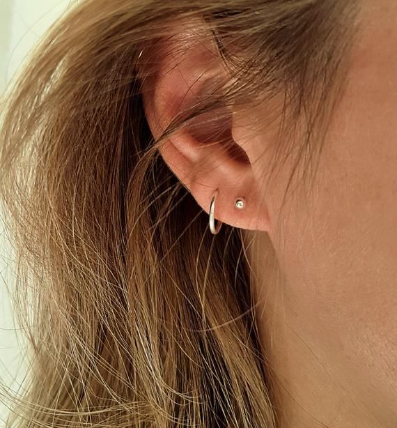 a close up of a person's ear wearing a pair of small hoop earrings