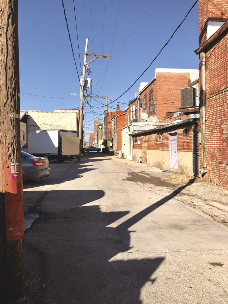 an empty street with cars parked on the side and power lines in the air above