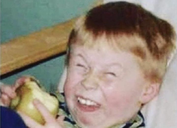 a young boy is smiling and holding an apple