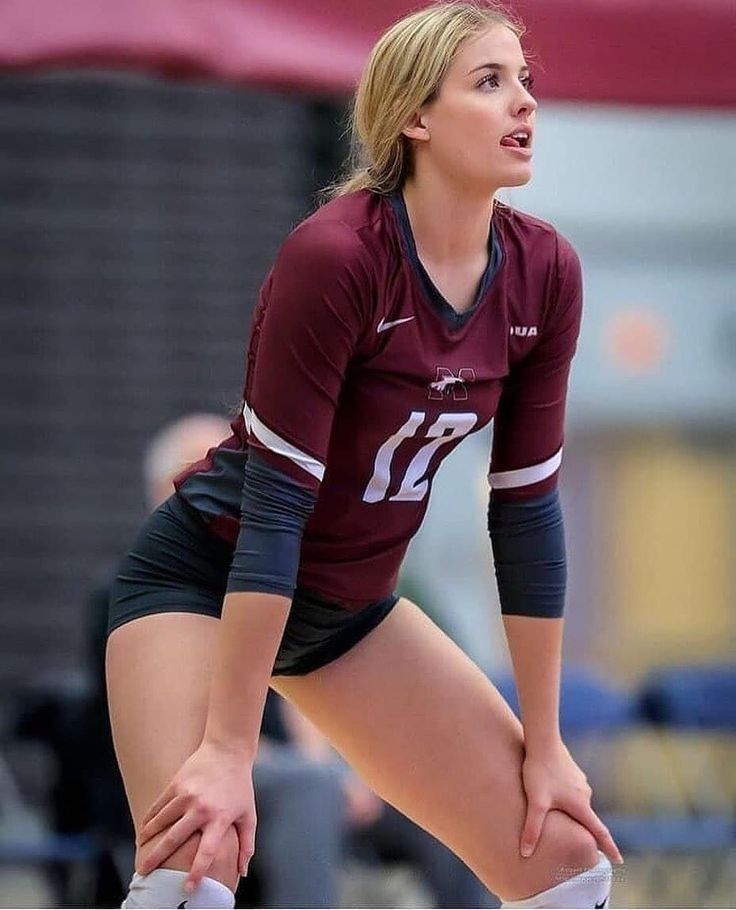 a female volleyball player is holding her knee in preparation for the ball to be hit