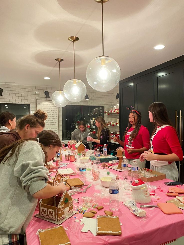 a group of people standing around a table covered in gingerbreads and frosting