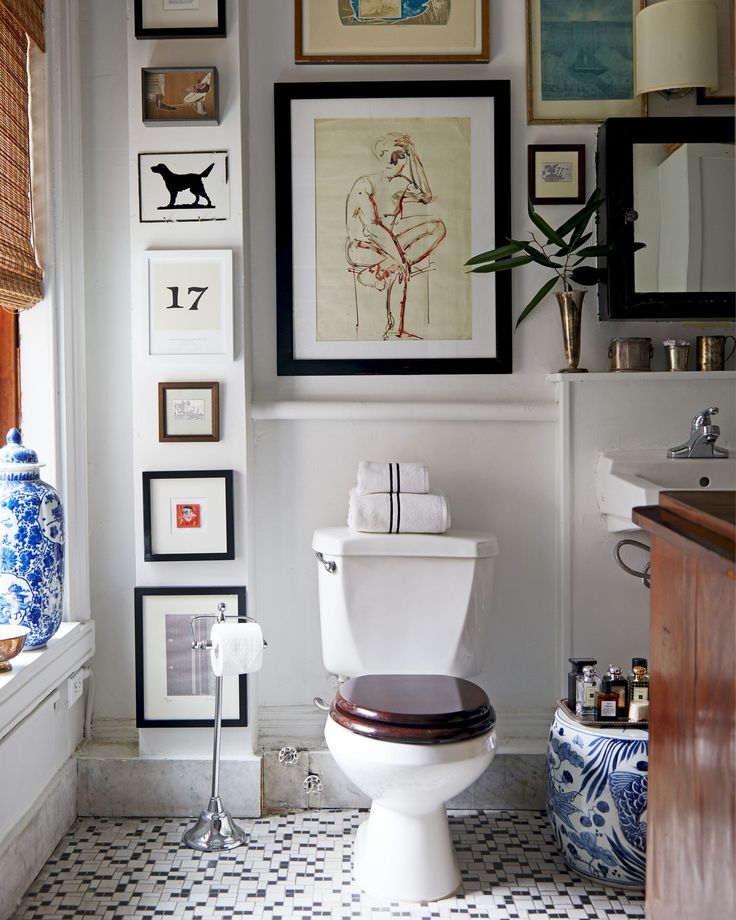 a white toilet sitting in a bathroom next to a window with pictures on the wall