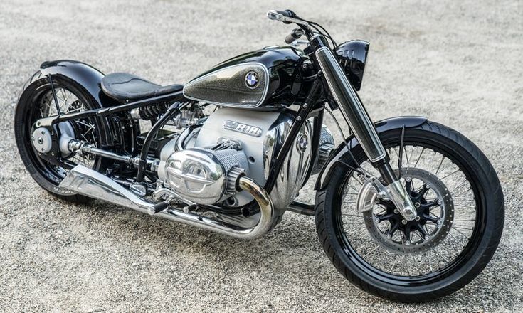 a black motorcycle parked on top of a parking lot next to a street filled with lots of gravel