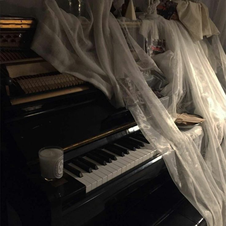 an old piano is covered with sheer curtains