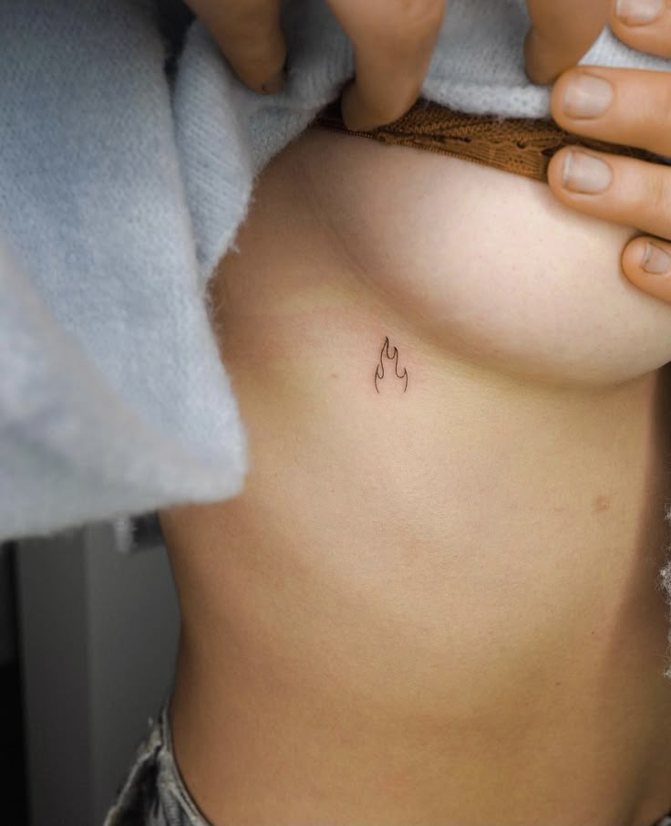 a close up of a person's stomach with small tattoos on the side and breast