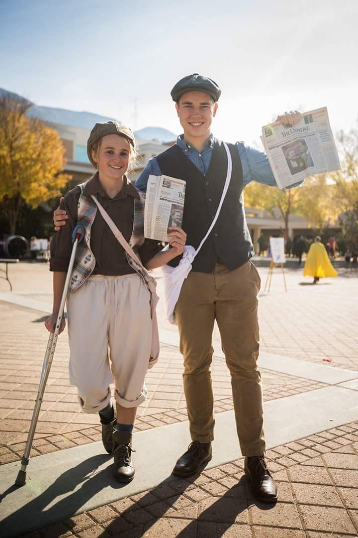 a man and woman are standing on the sidewalk with newspapers in their hands while they hold up newspaper