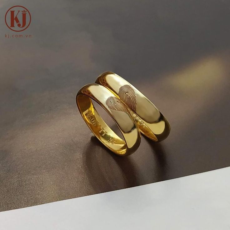 two gold rings sitting on top of a table