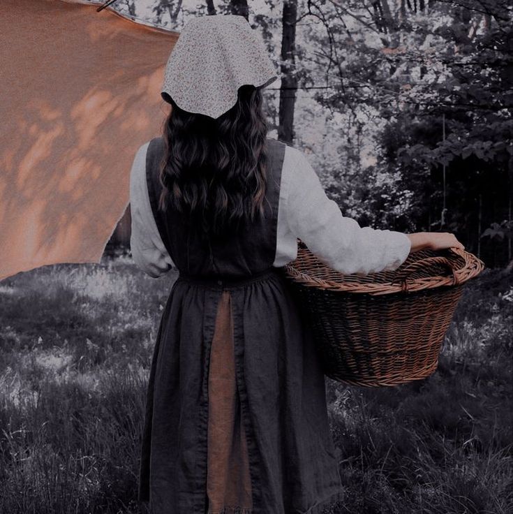 a woman with long hair holding a basket in her hand and an umbrella over her head