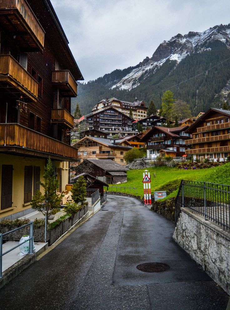 an empty street with buildings and mountains in the background