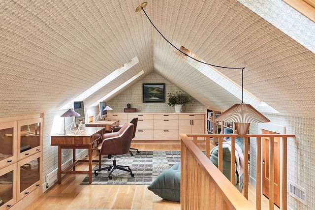 an attic office with wooden floors and white walls, along with a desk in the corner