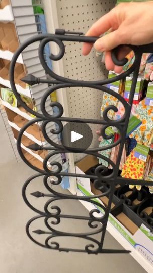 a person is holding a black metal rack in a store with other items on the shelves