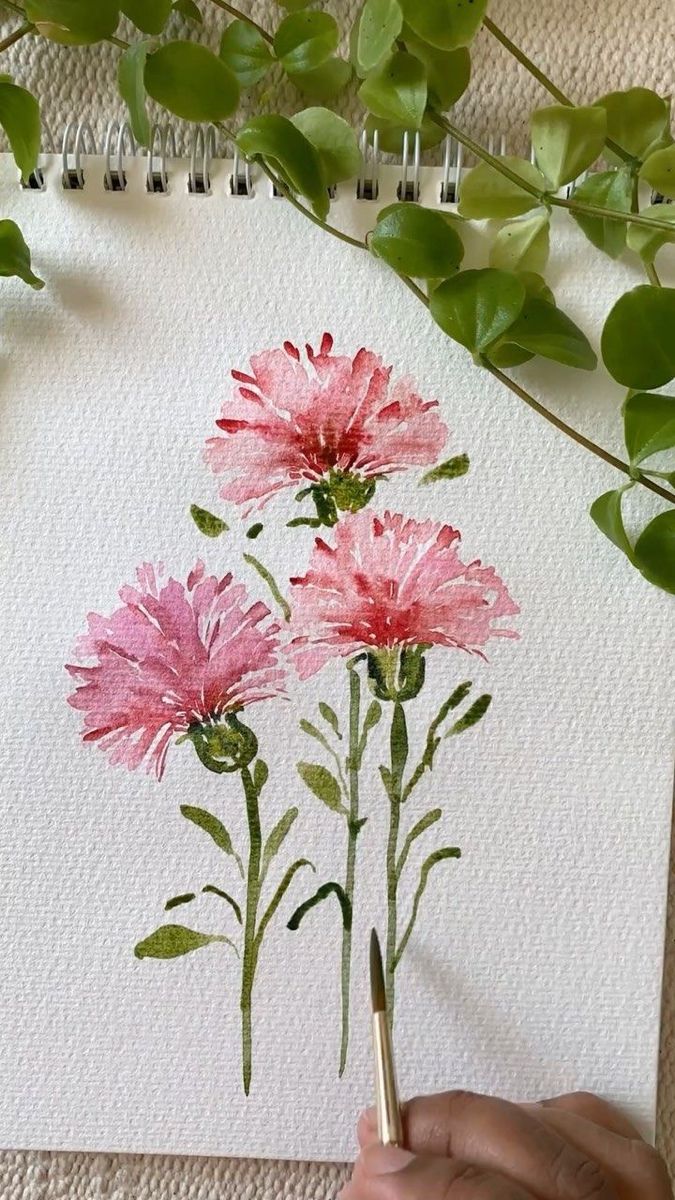 someone is drawing flowers with watercolors on paper