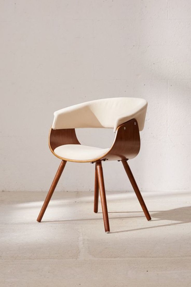 a white chair sitting on top of a cement floor next to a wall with a wooden frame