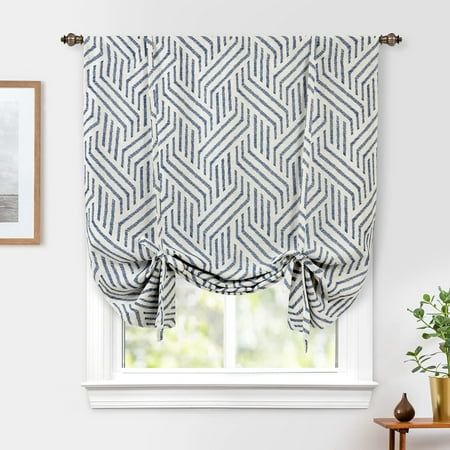 a window with a blue and white patterned roman blind in front of a potted plant