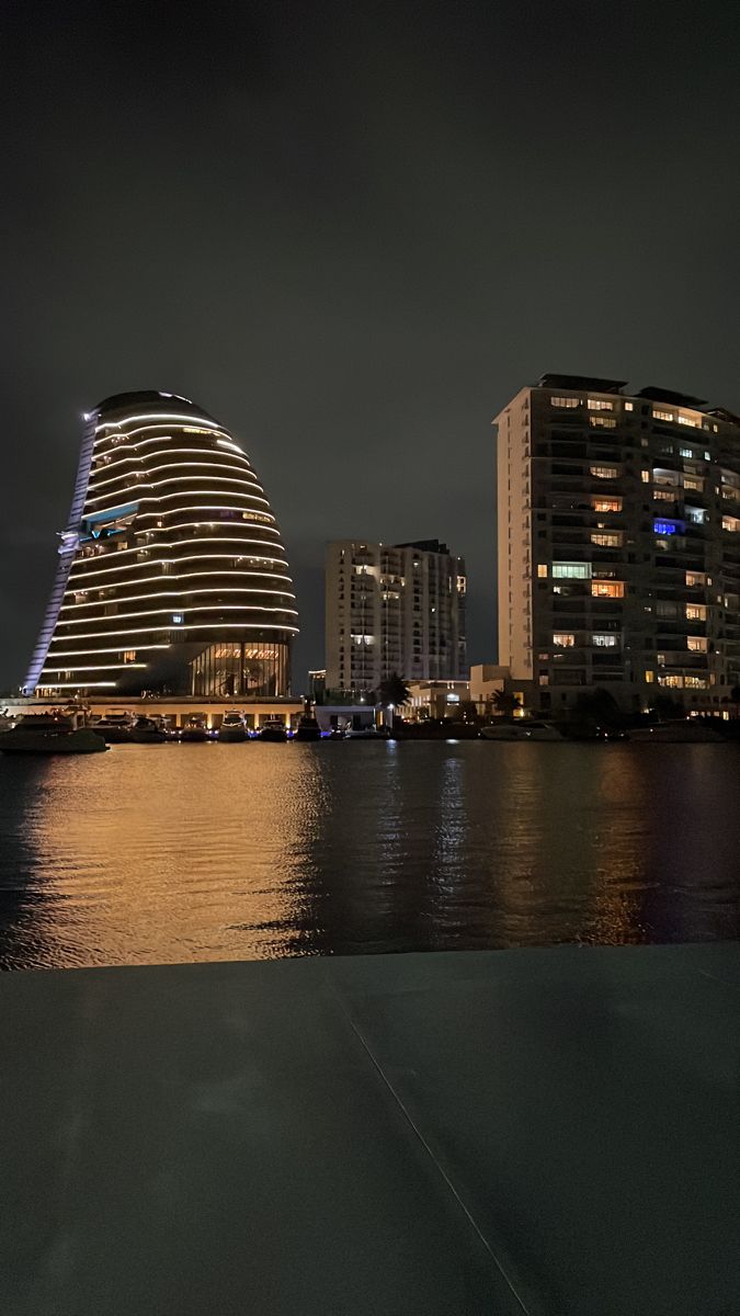 the city skyline is lit up at night with lights reflecting in the water and buildings on both sides