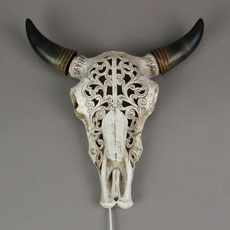 an ox skull with long horns and intricate designs on it's face is displayed against a gray background