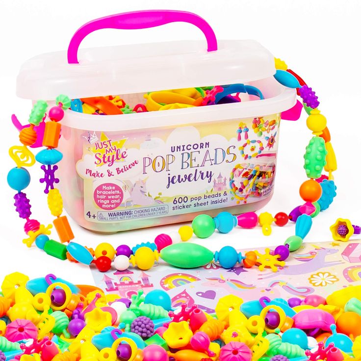 a plastic tub filled with lots of colorful beads next to a pink handle bag full of candy