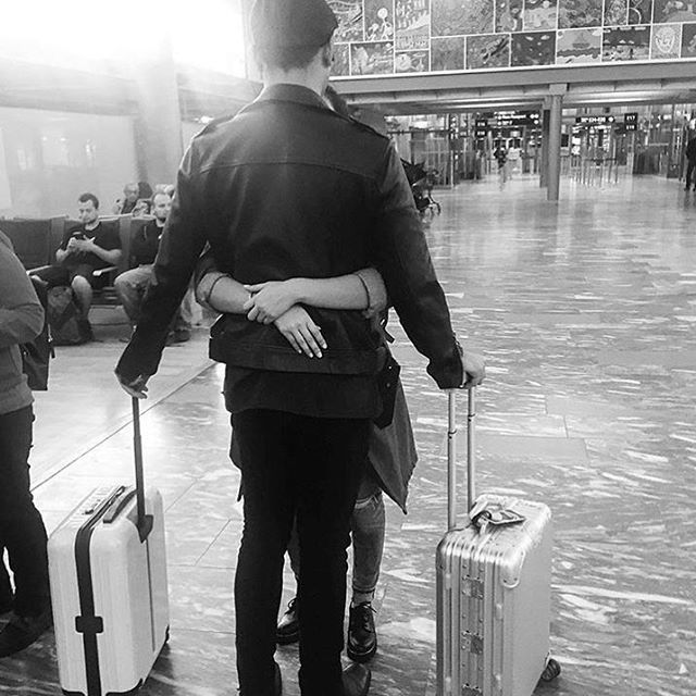 two people are walking with their luggage in the rain