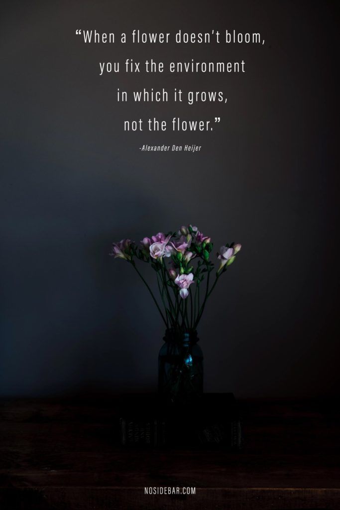 a vase filled with flowers sitting on top of a wooden table next to a wall