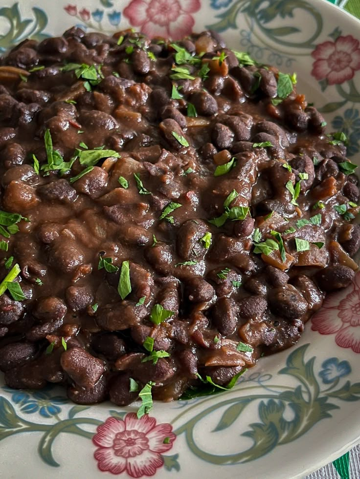 a close up of a plate of food with beans and herbs on it, surrounded by flowers