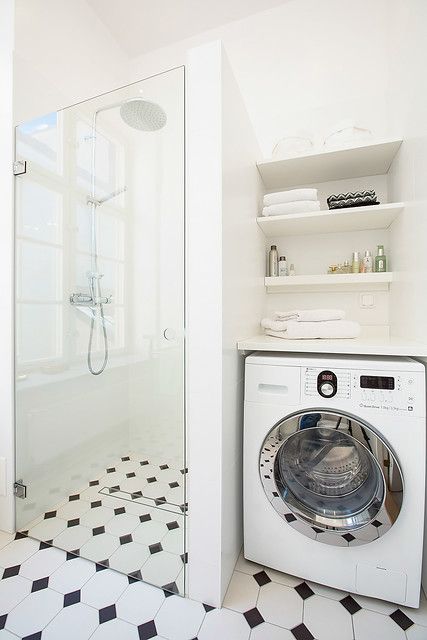 a washer and dryer in a white bathroom with black and white flooring