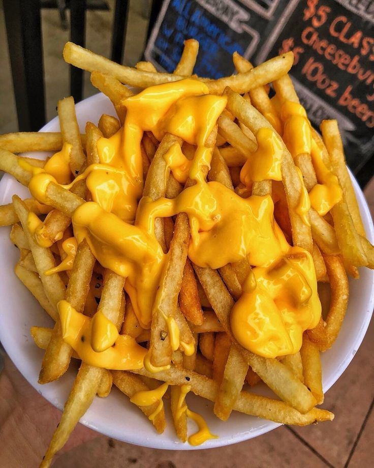 a plate full of cheese fries on a table