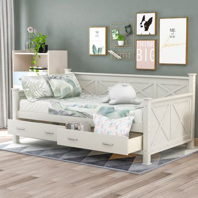 a white daybed with drawers underneath it in a room that has blue walls and hardwood floors