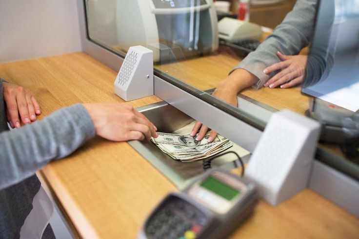 two people at a counter counting money in front of a mirror with the reflection of another person's hand