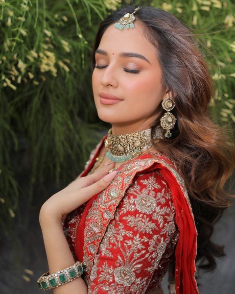 a woman in a red and gold outfit with her hands on her chest, posing for the camera