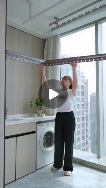 a woman standing in front of a washer and dryer holding the door open