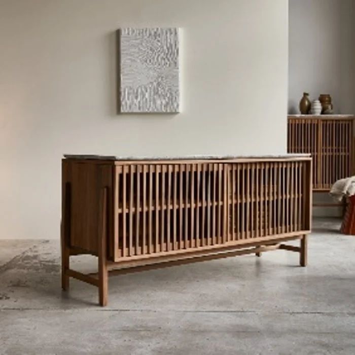 a wooden crib sitting in the middle of a living room next to a painting