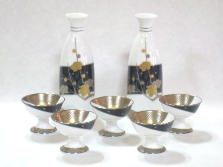 six silver and black glass bowls next to a bottle