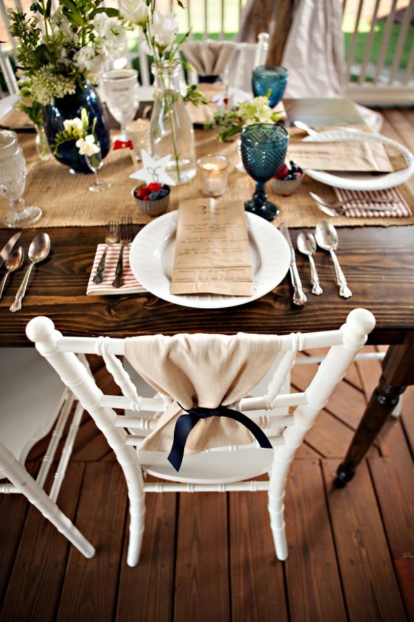 a wooden table topped with white plates and place settings