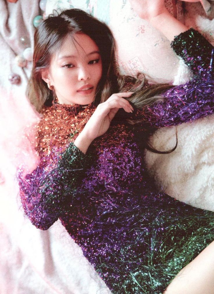 a woman laying on top of a bed wearing a purple and green knitted sweater