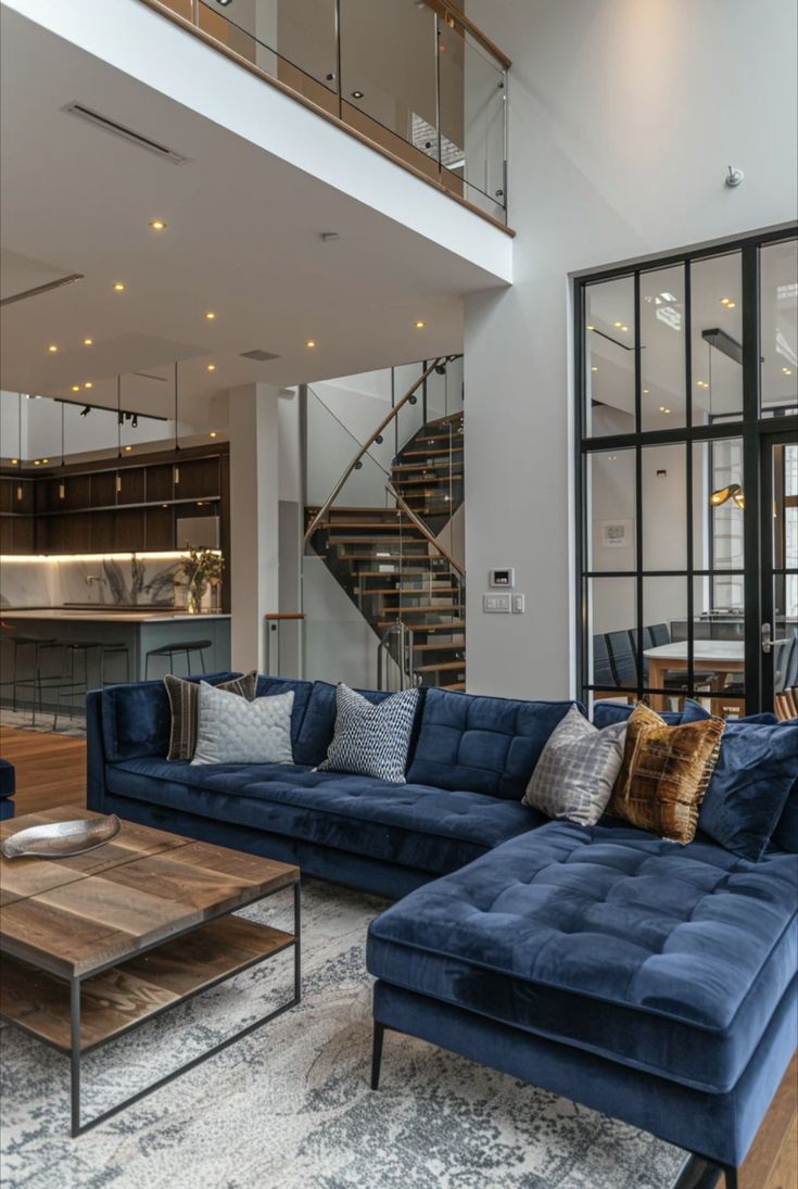 a living room filled with blue couches next to a wooden coffee table and stairs