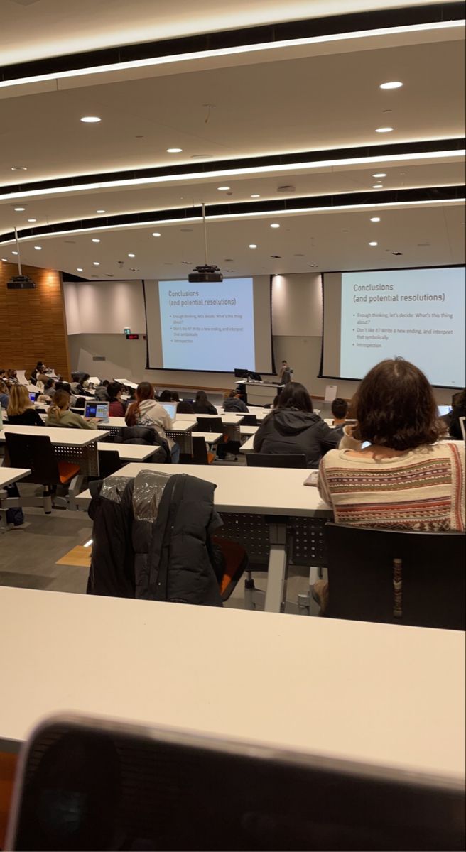 people are sitting at desks in front of large screens and projector screens on the wall