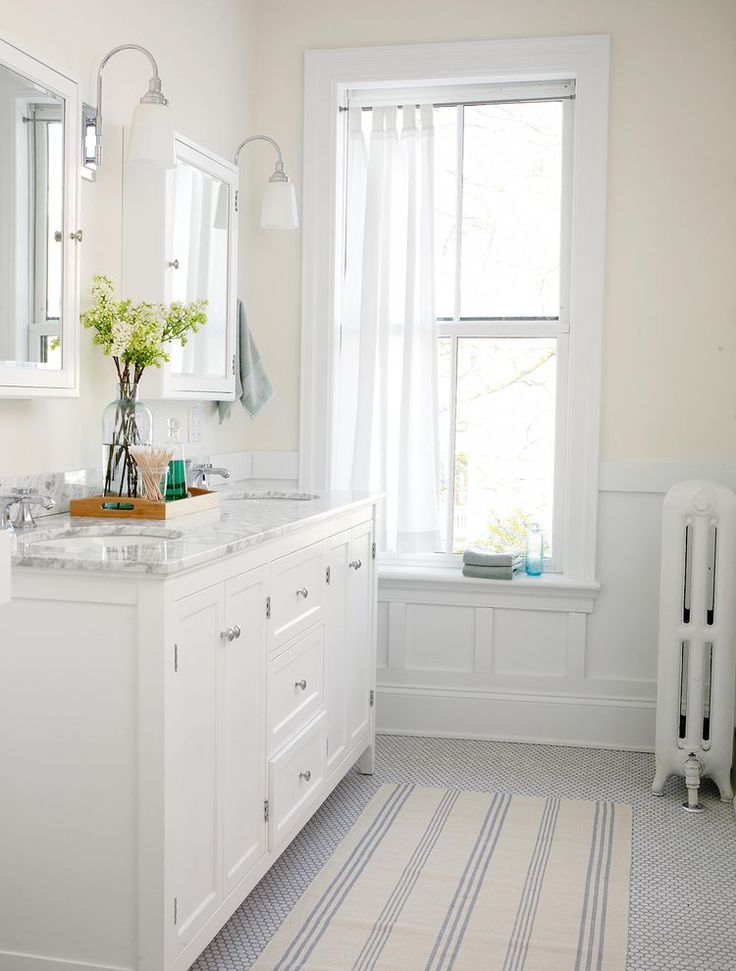 a white bathroom with two sinks and a large window