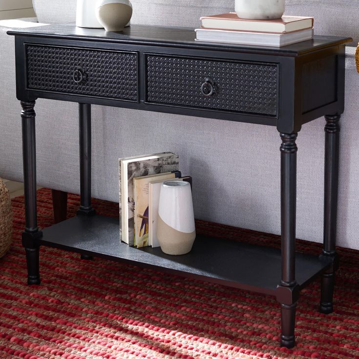 a black console table with two drawers and a magazine on the bottom shelf next to it