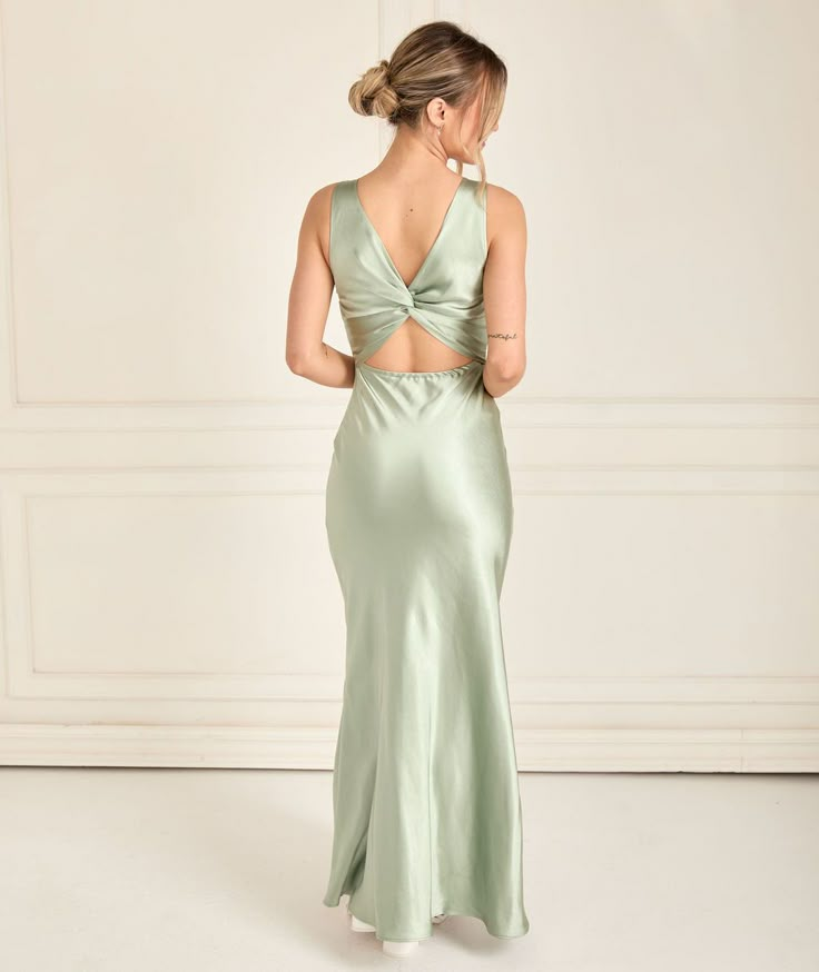 a woman in a long green dress looking back at the camera and wearing an open back gown