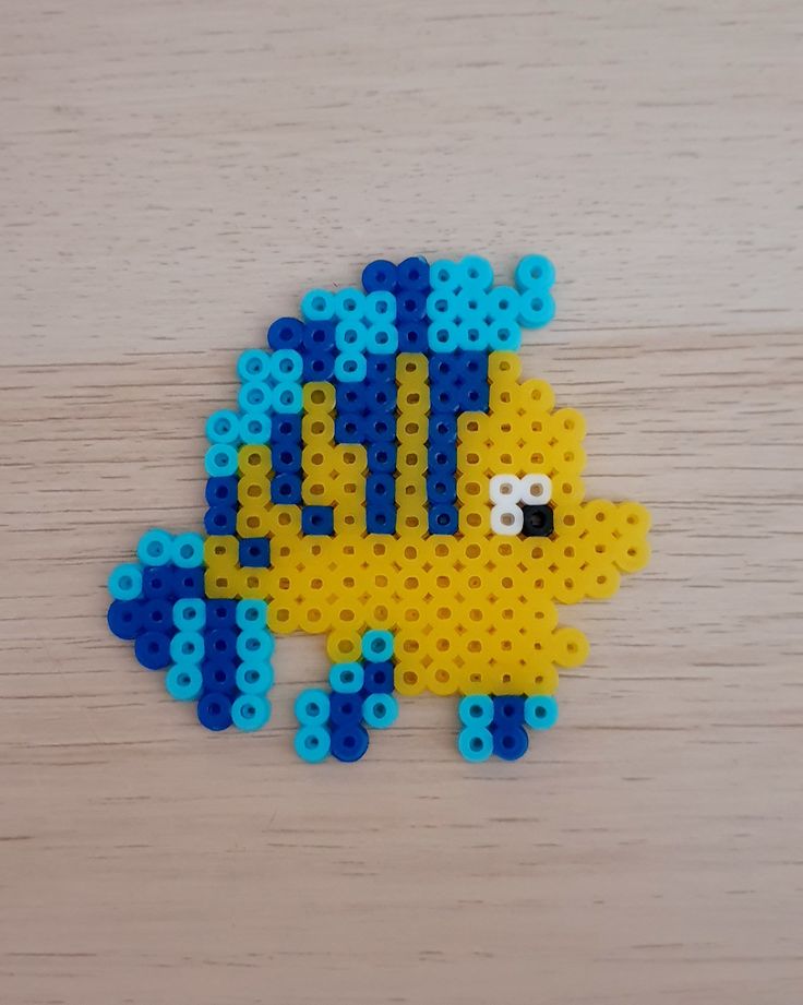 a yellow and blue sheep made out of legos on top of a wooden table