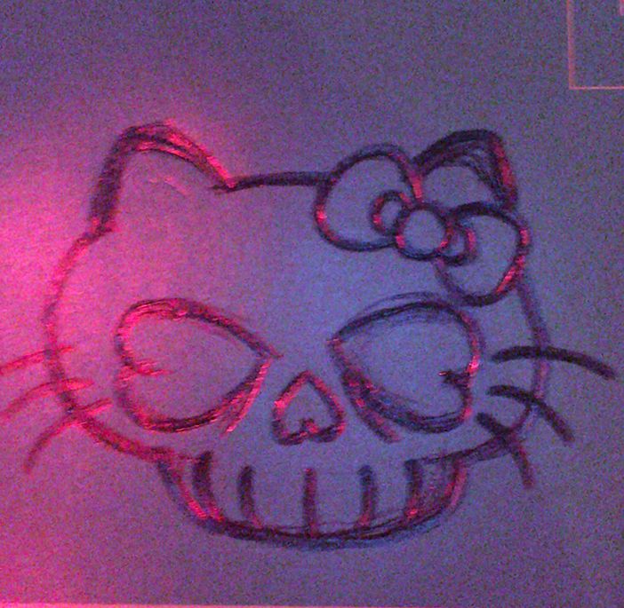 a drawing of a hello kitty face on a wall with red light in the background