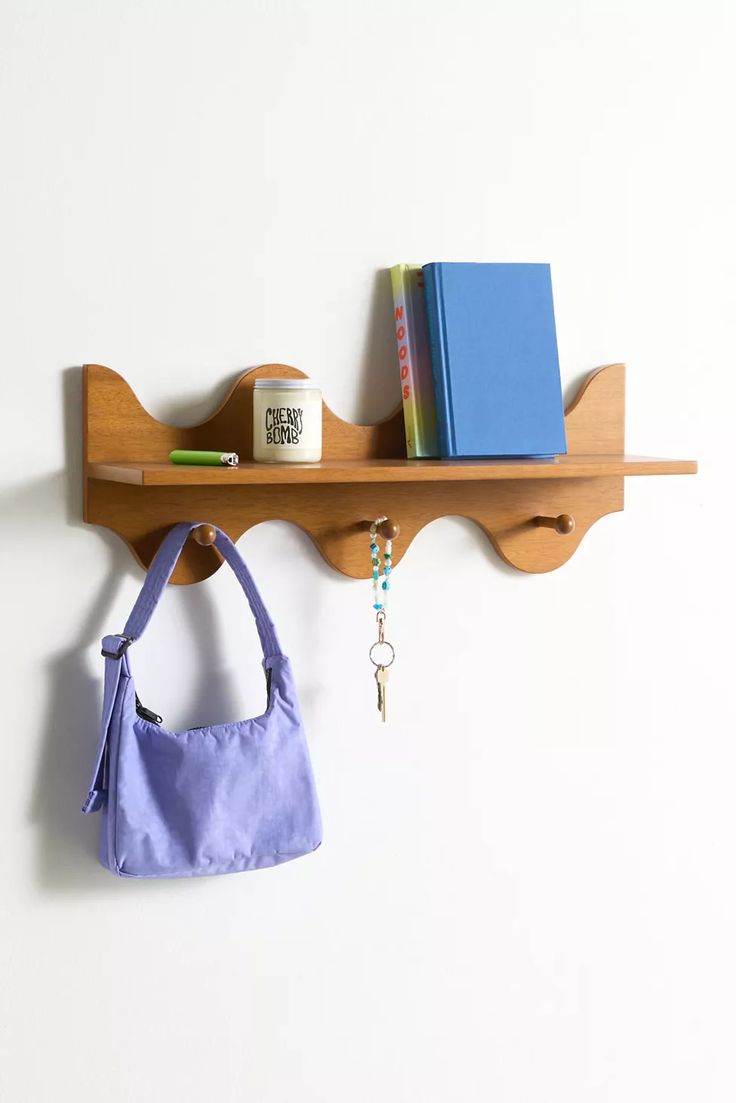 a wooden shelf with a purse and books on it next to a wall mounted key rack