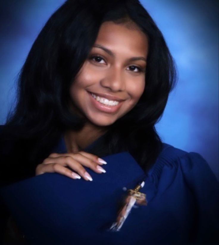 a woman with long black hair holding a blue book and wearing a cross on it