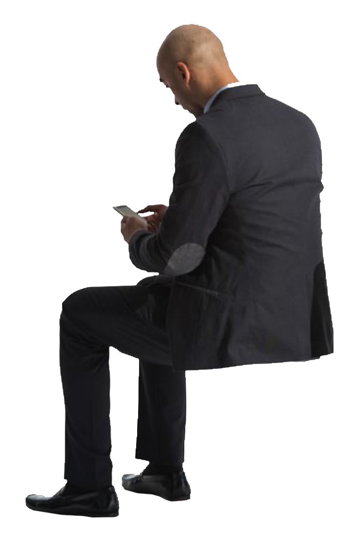 a man in a suit sitting on a chair looking at his cell phone