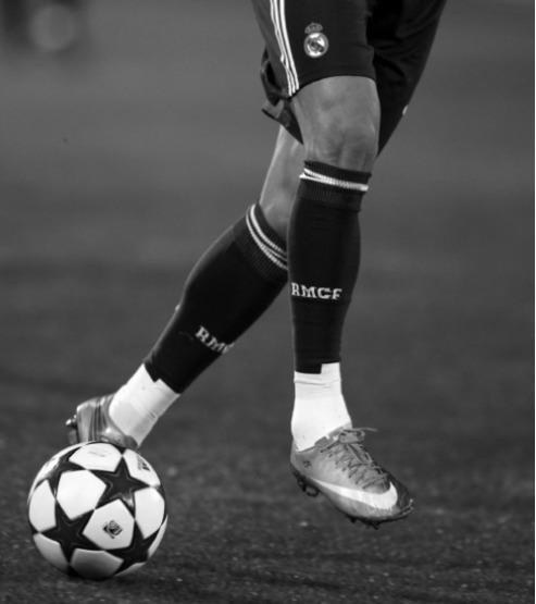 black and white photograph of a soccer player with his foot on the ball in front of him