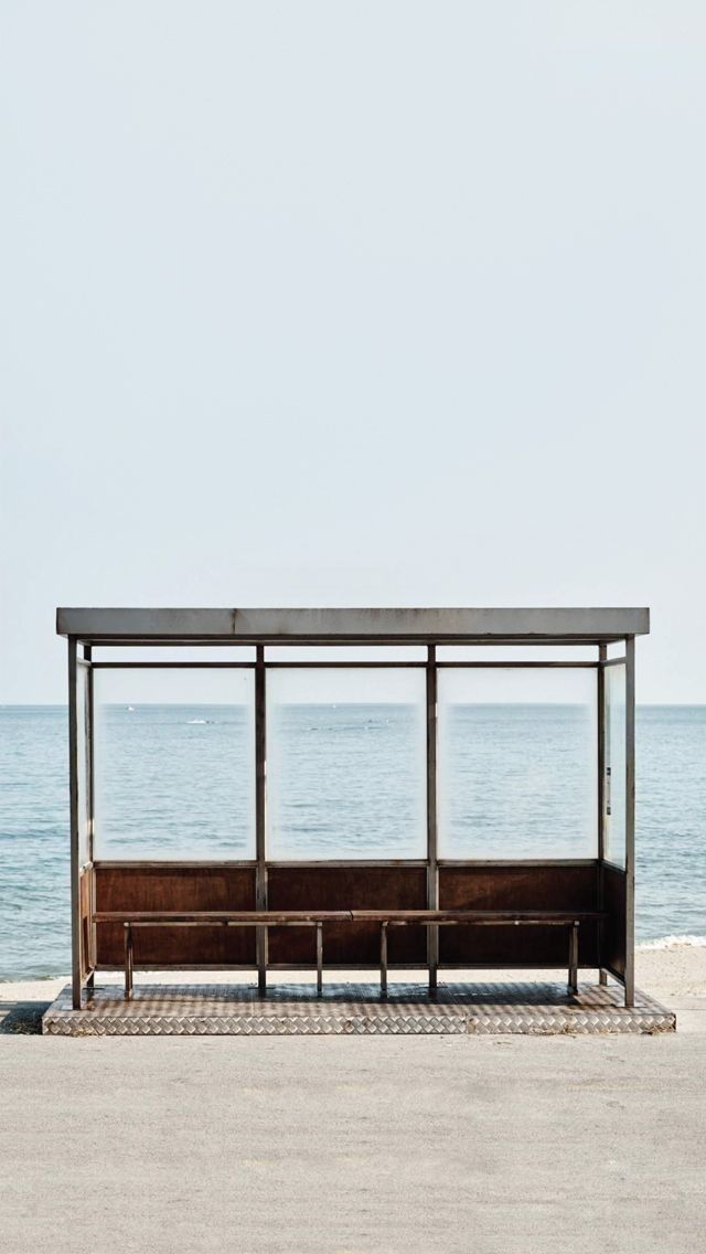 a bench sitting in front of the ocean under a blue sky with no one on it