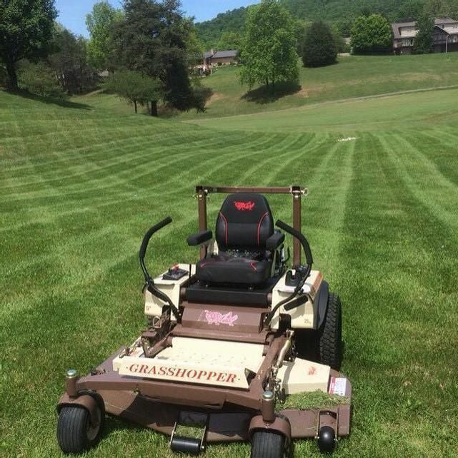 a lawn mower sitting in the middle of a field with grass on both sides