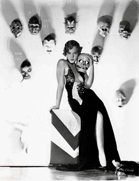 an old black and white photo shows two women in evening dresses with skulls on the wall behind them